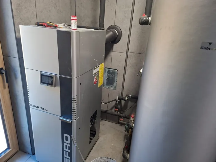 Zbliżenie na kocioł pelletowy i przyłącza hydrauliczne